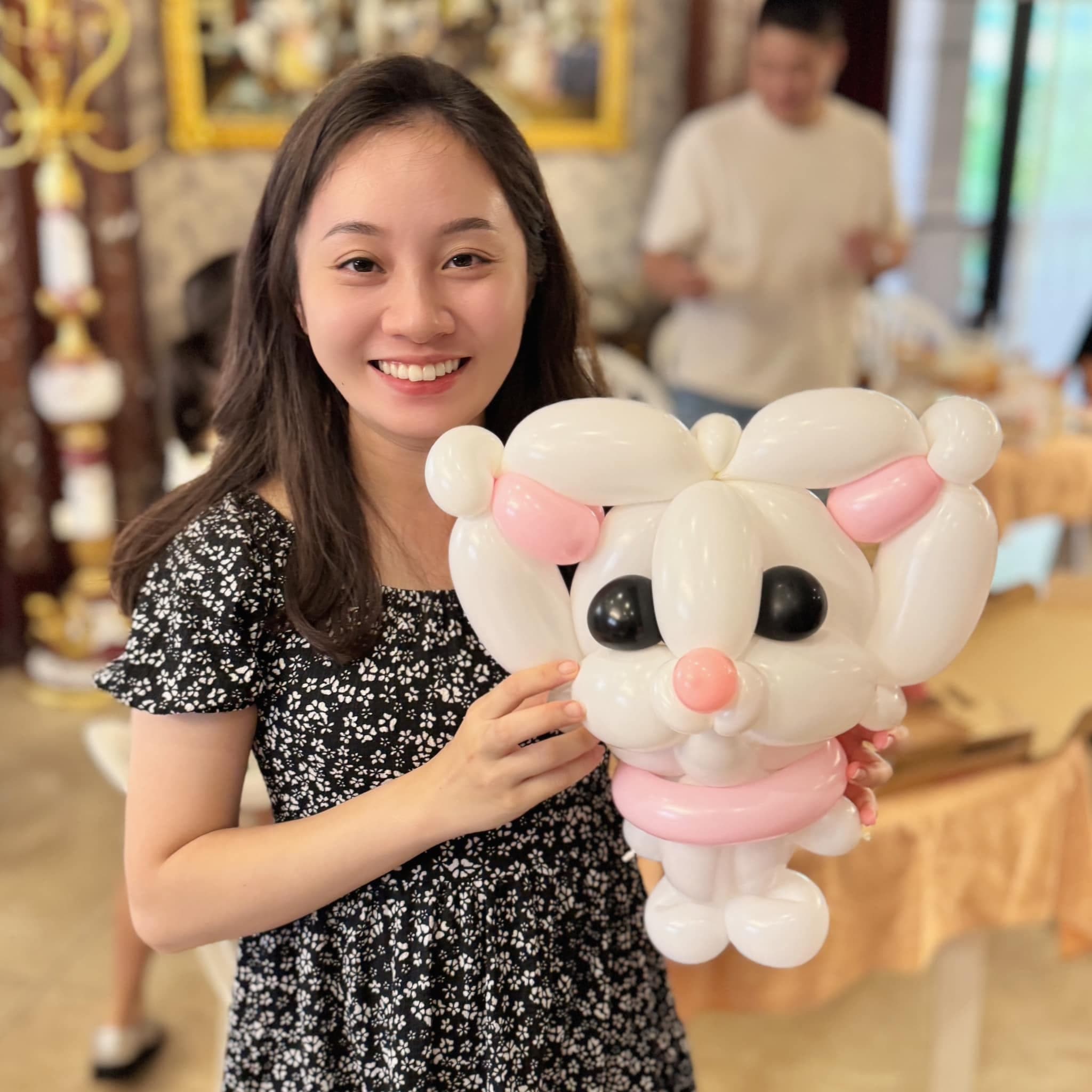 女生抱著戴粉紅蝴蝶結、粉紅鼻子的白色貓咪造型氣球