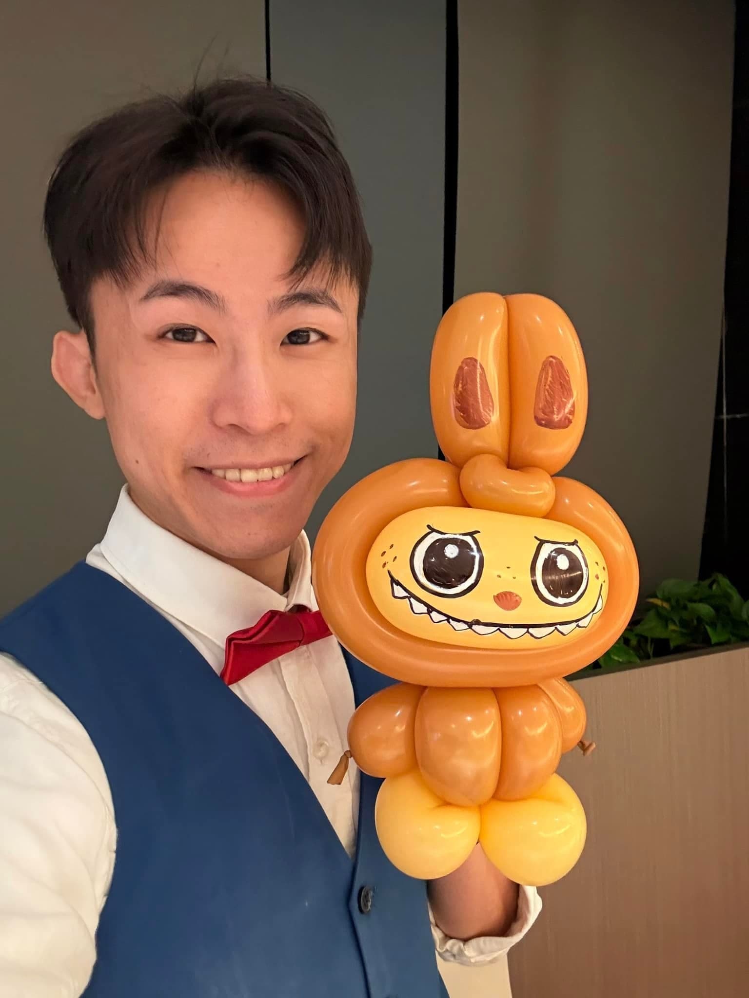 10 月場：柯男在婚禮會場自拍，舉著剛折好的 Labubu 造型氣球