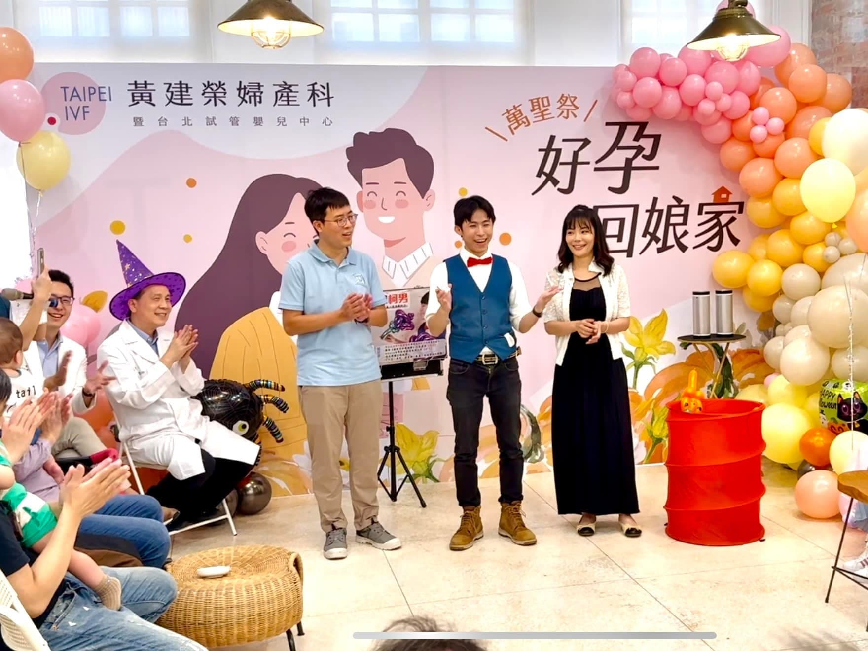 萬聖節親子活動舞台，背板旁是粉橘黃漸層氣球花圈，台上主持人與醫師面對觀眾