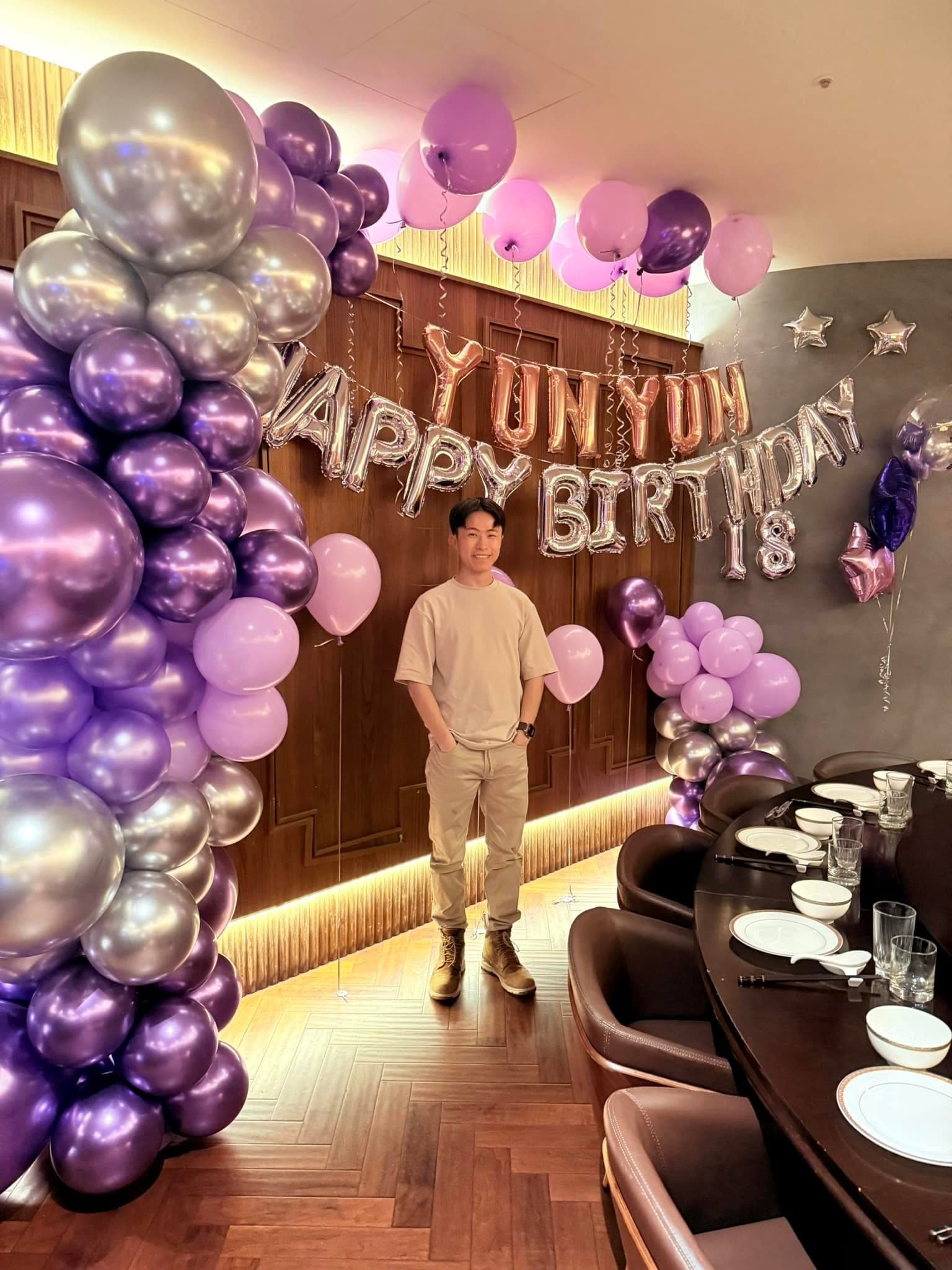 11 月紫銀場：柯男站在紫色生日佈置牆前，牆上有 18 數字氣球