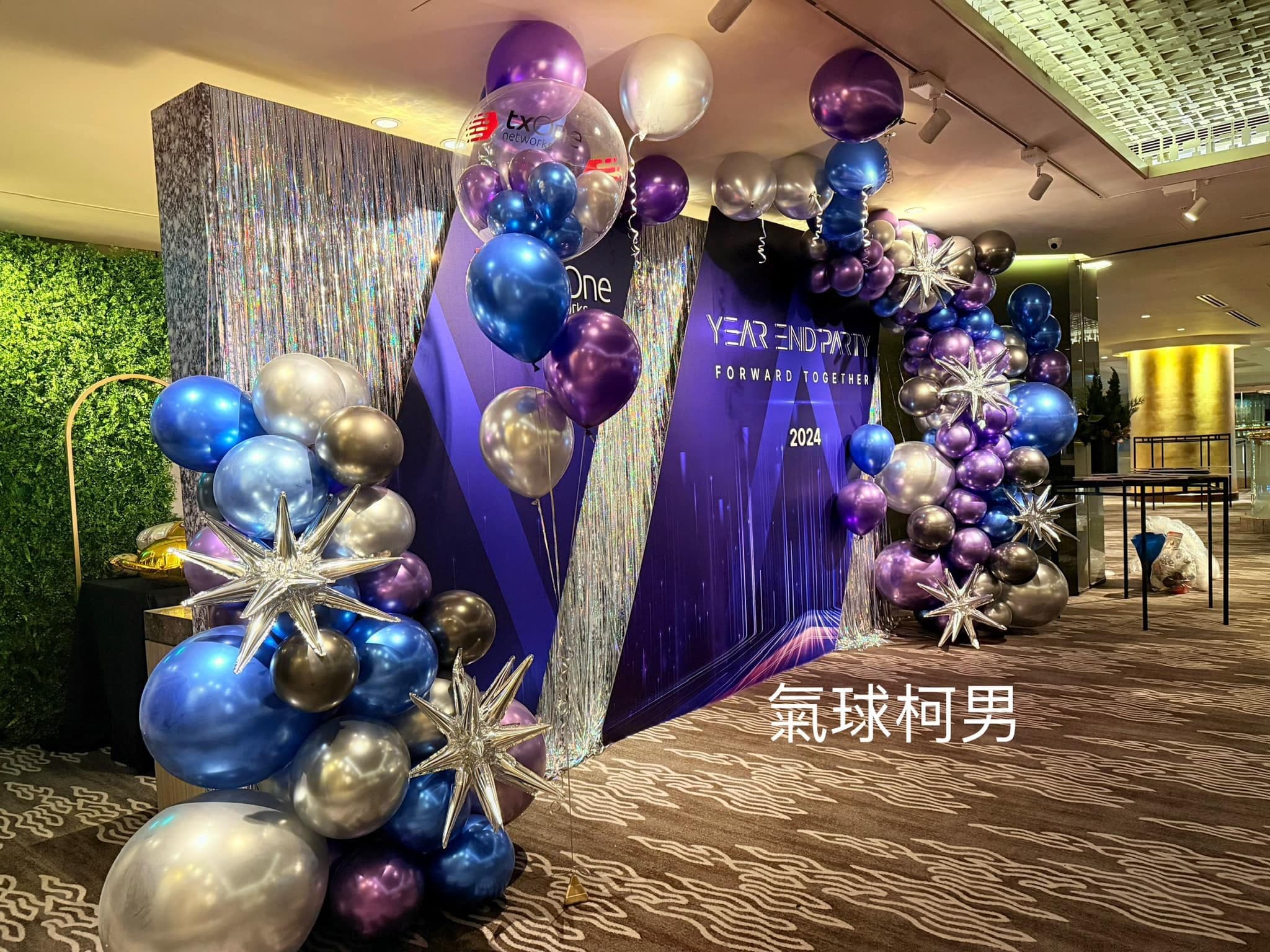 從側面看尾牙背板，前方金屬色氣球堆裡插著兩顆銀色星芒鋁箔氣球