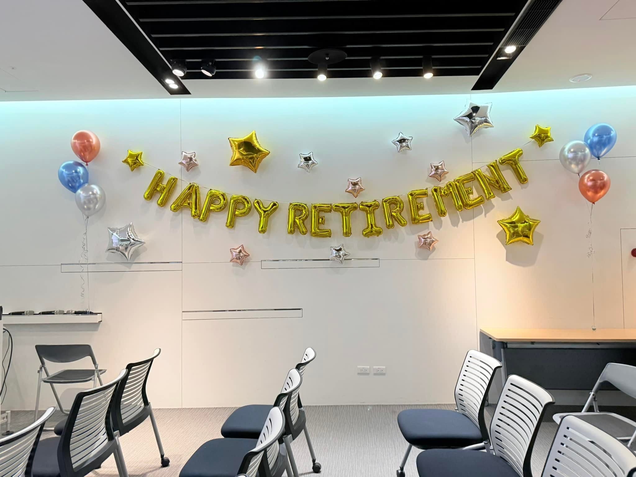 會議室白牆的金色 HAPPY RETIREMENT 字母氣球與金銀星星鋁箔