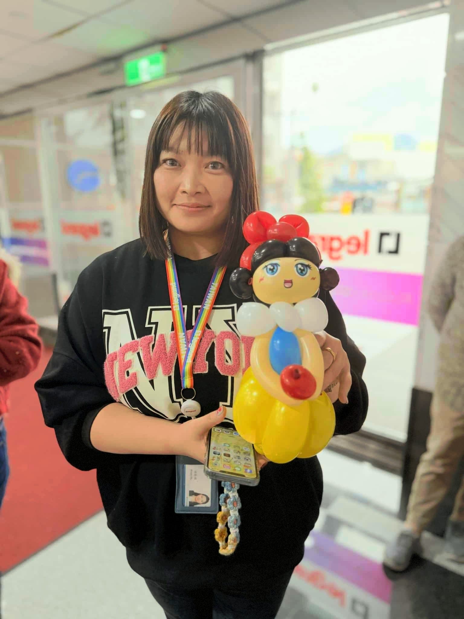 穿黑色長袖上衣的女士抱著白雪公主造型氣球，藍色上衣、黃色裙子和紅色蝴蝶結