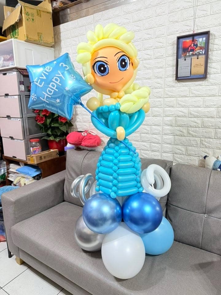 冰雪奇緣艾莎氣球人偶，金色髮辮、藍色禮服裙擺，站在金屬藍銀白氣球底座上，手持藍色星星氣球