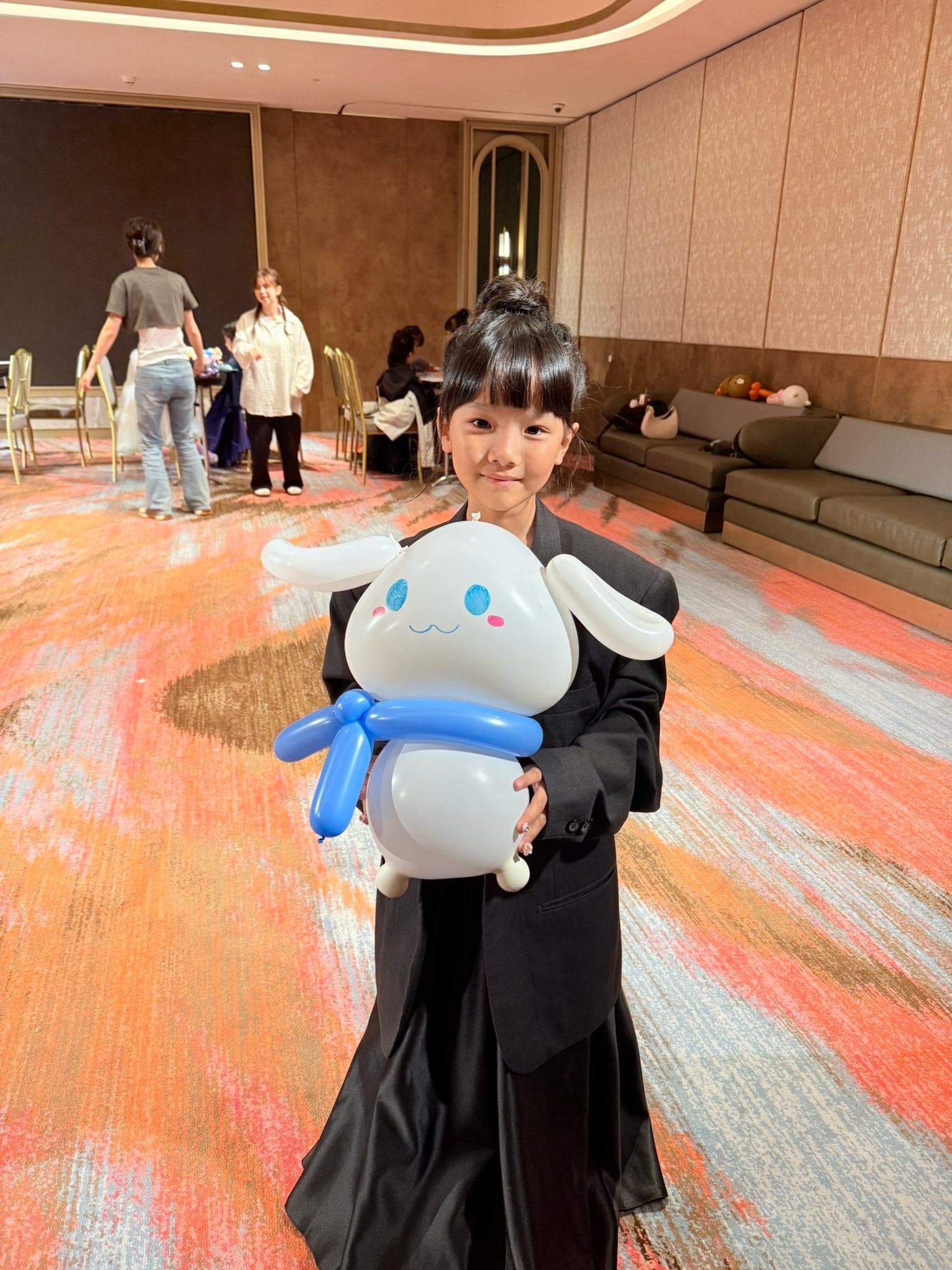 女孩雙手抱著白色大耳朵、藍色圍巾的大耳狗造型氣球