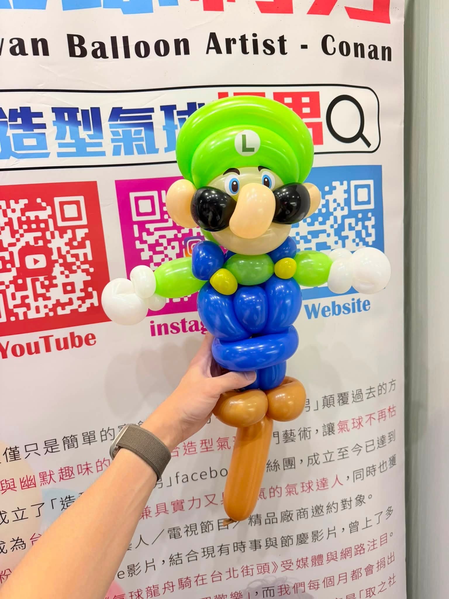 綠色帽子、藍色吊帶褲的路易吉造型氣球，背景是氣球柯男的 QR code 看板