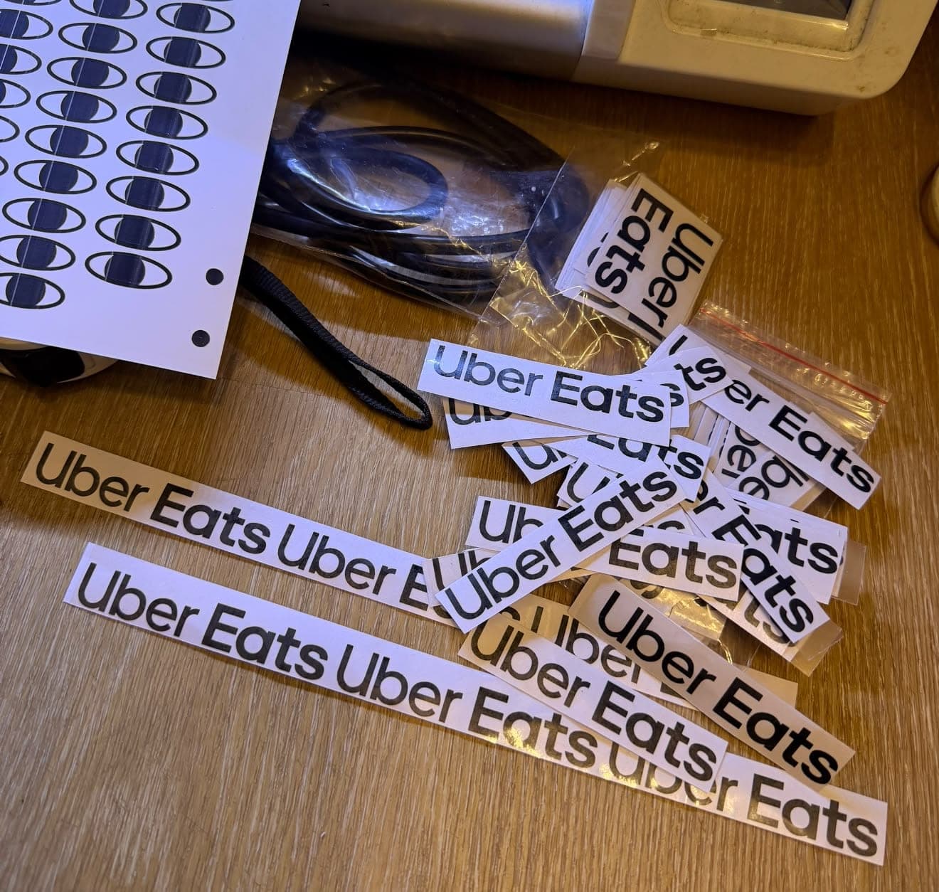 桌上散落裁切好的 Uber Eats 字樣貼紙與一整張眼睛貼紙，是活動前一天準備的材料