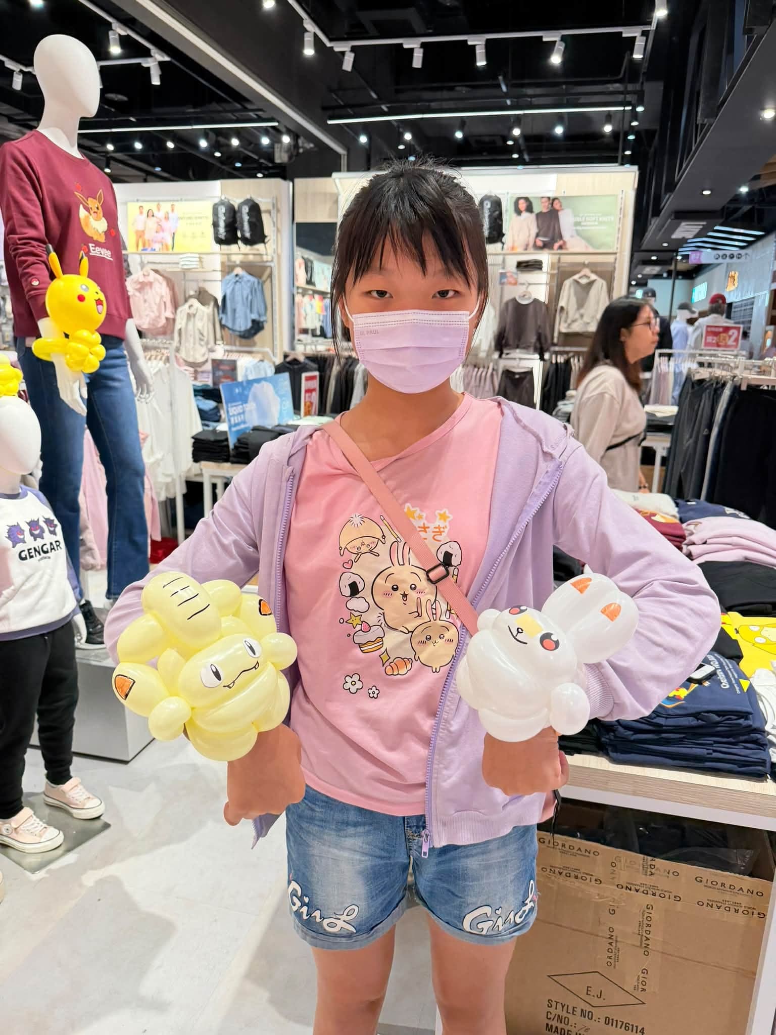 戴口罩的女孩兩手各戴一個氣球手環，一個黃色寶可夢造型、一個白色橘耳角色造型