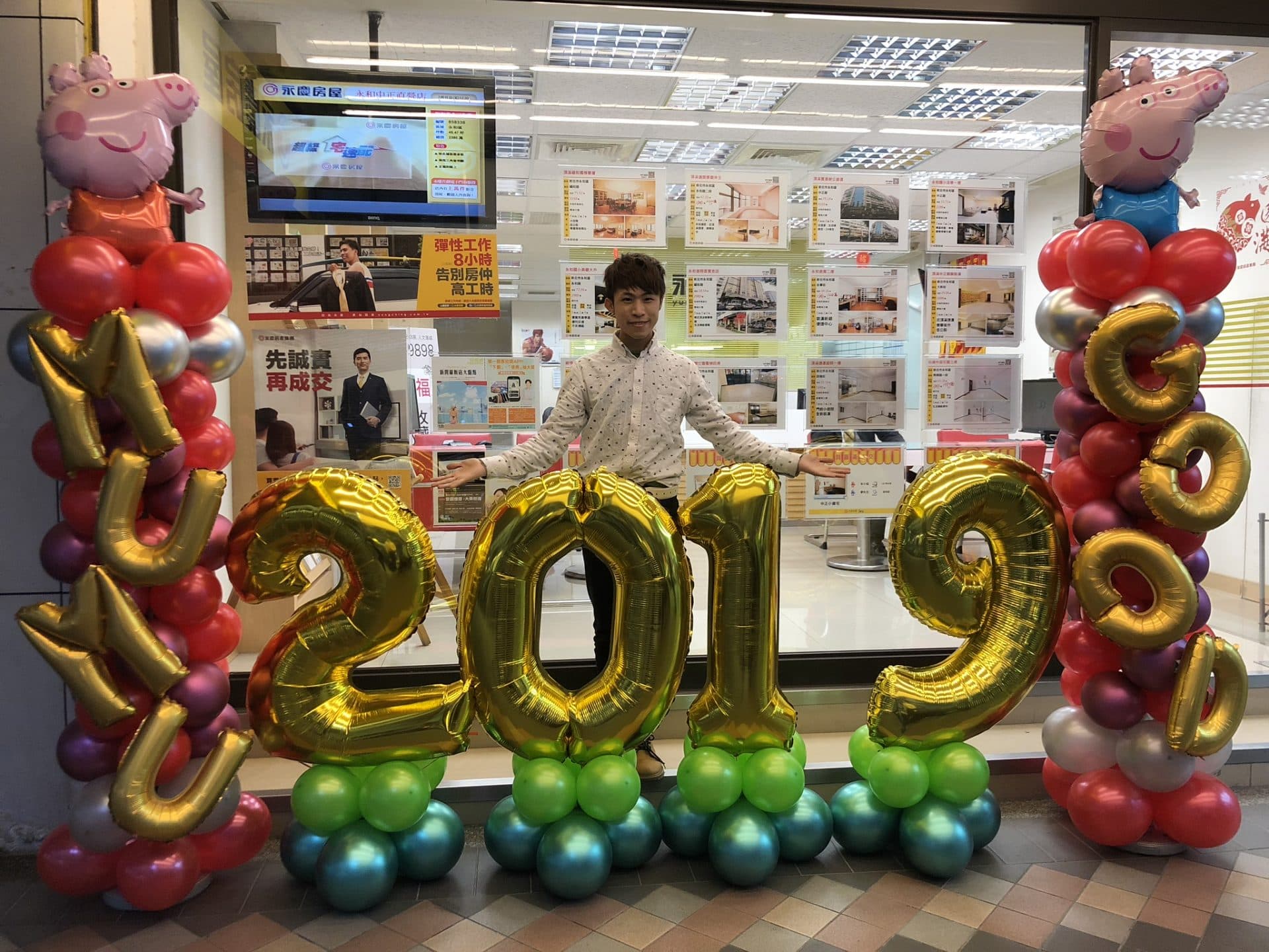 房仲店門口的紅銀紫氣球柱，MUMU 與 GOOD 金色字母、2019 數字氣球與佩佩豬鋁箔氣球