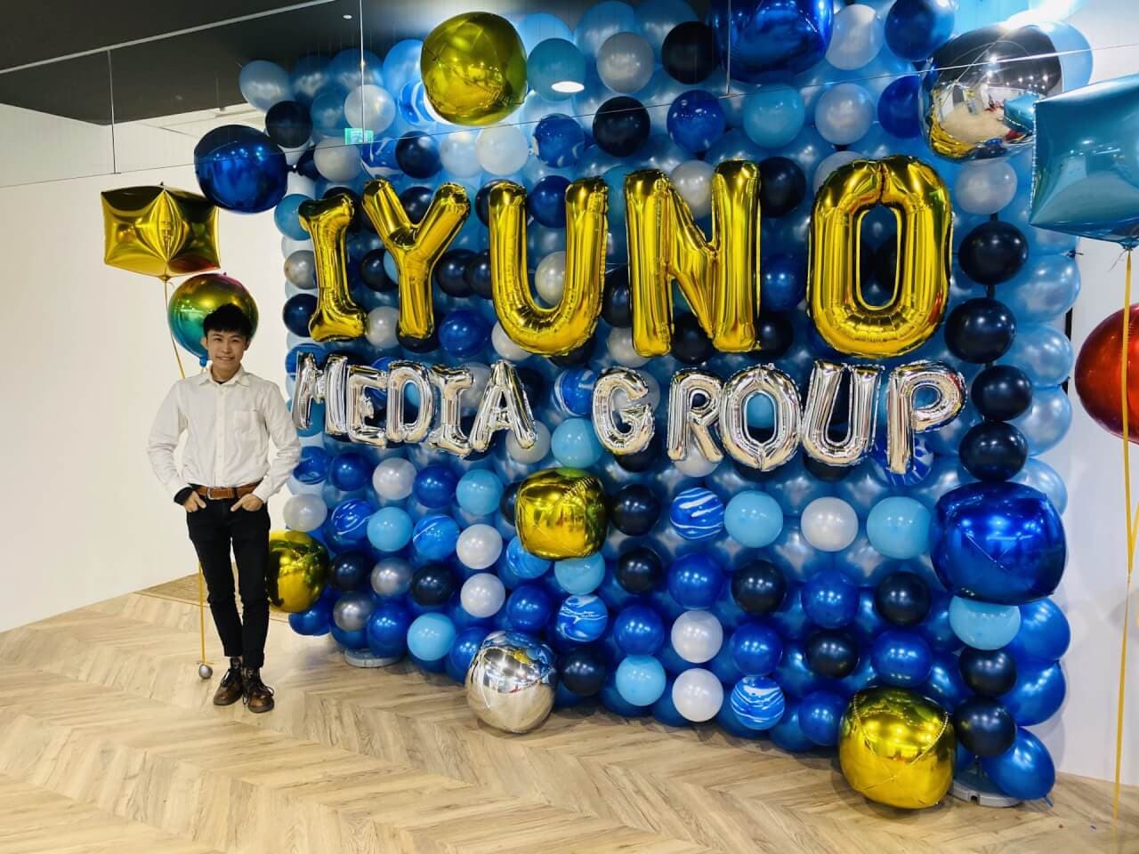 藍銀色系氣球牆，金色與銀色字母氣球拼出 IYUNO MEDIA GROUP