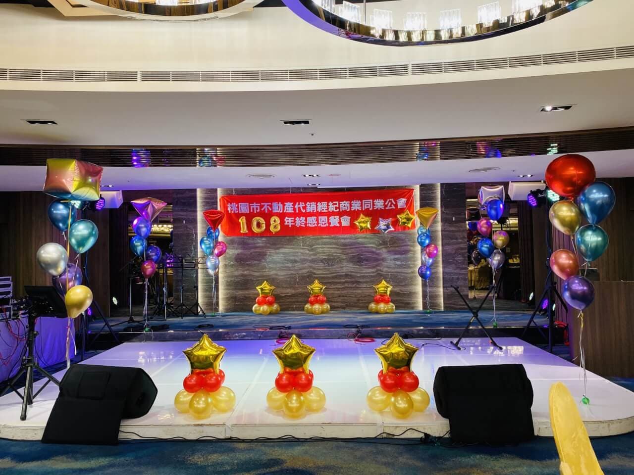 代銷公會年終感恩餐會舞台，前緣三組紅金星星氣球擺飾