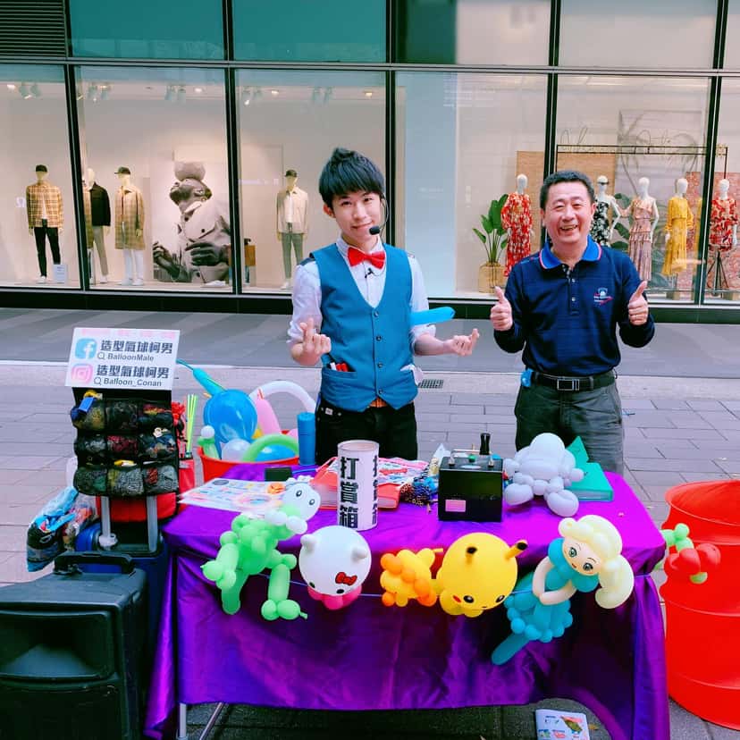 紫色桌布的街頭氣球攤位,前方掛著皮卡丘、Hello Kitty 等造型氣球