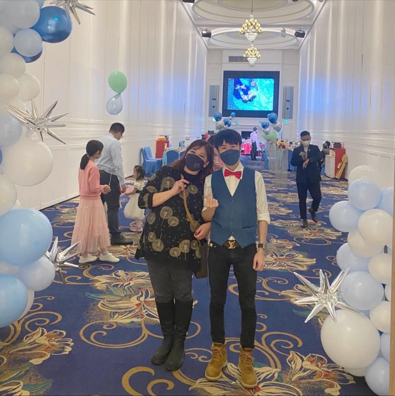 柯男與邀請的客人在藍白氣球柱夾道的婚宴走道上合照