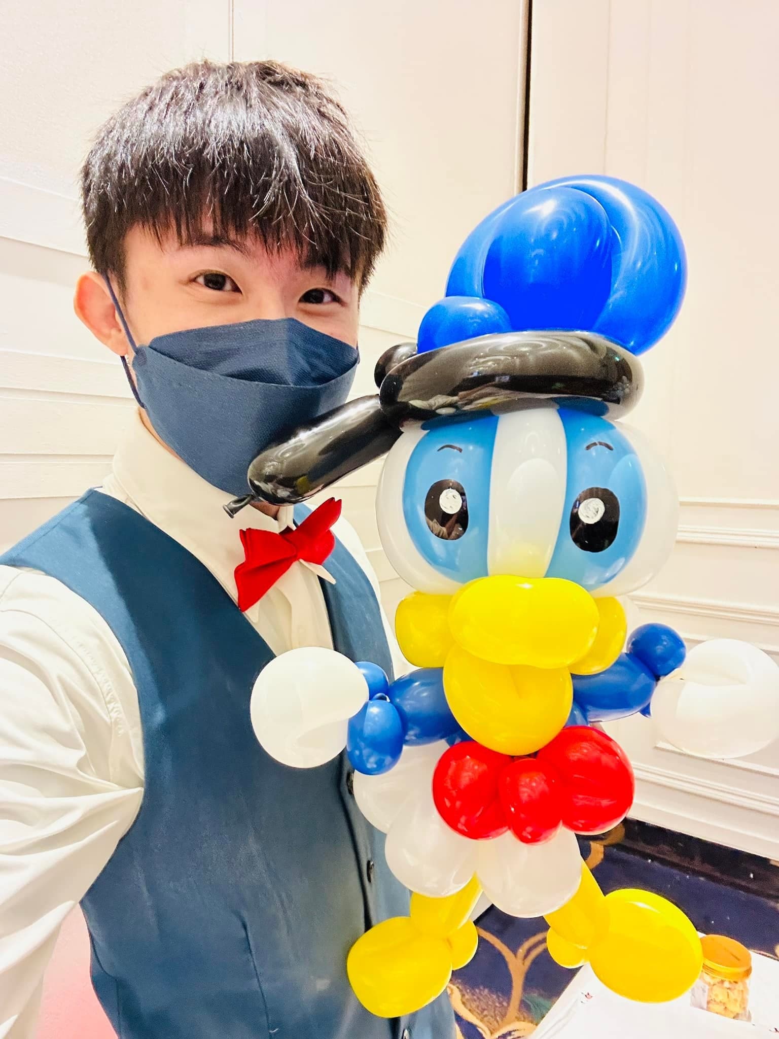 柯男自拍,旁邊是戴藍色帽子、黃色嘴巴的唐老鴨造型氣球