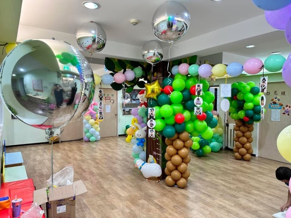 幼兒園大廳中央的氣球大樹,咖啡色樹幹配綠色樹冠,上方吊著銀色鏡面大氣球