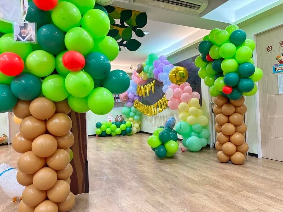 走廊兩側的氣球椰子樹,盡頭是掛著 HAPPY GRADUATION 字母的彩虹拱門