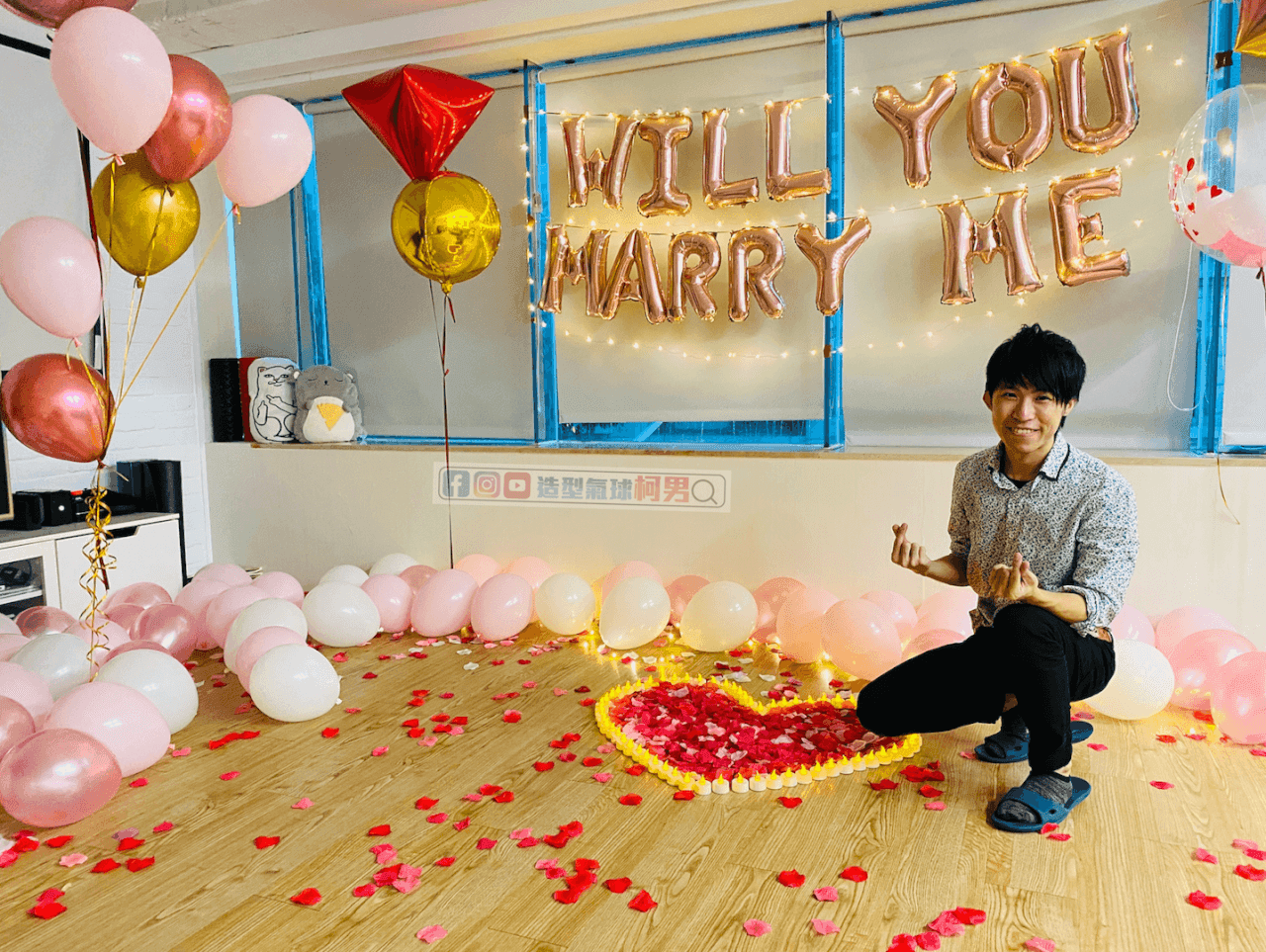 我蹲在玫瑰花瓣蠟燭愛心旁比愛心,後方是 WILL YOU MARRY ME