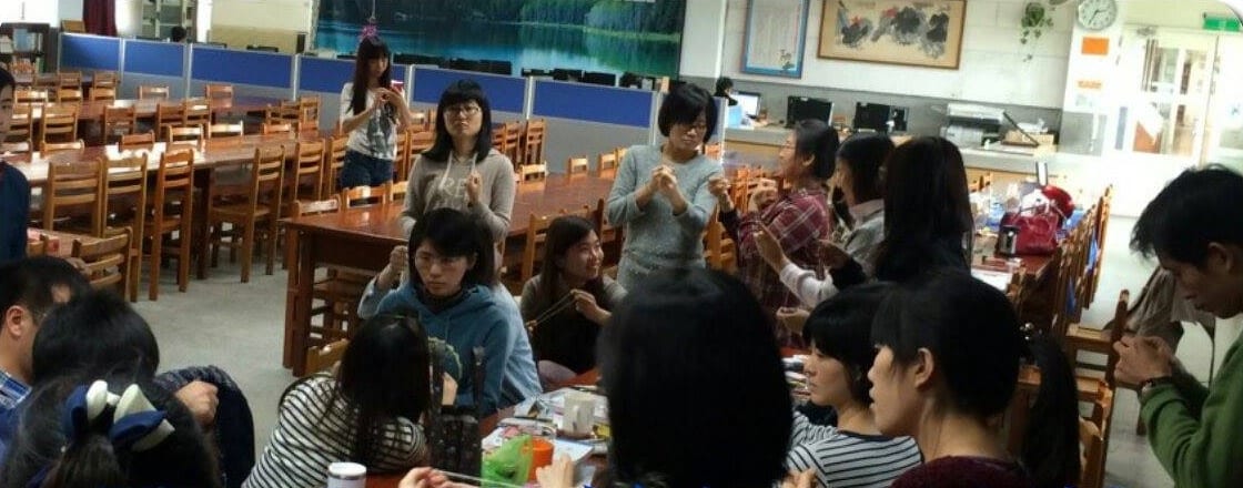 國中老師們圍坐長桌，認真練習剛學會的魔術