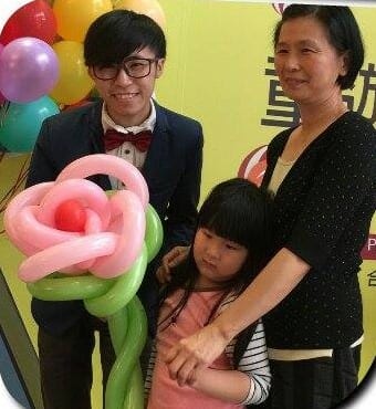 柯男與阿嬤、小女孩合照,小女孩拿著粉紅玫瑰造型氣球