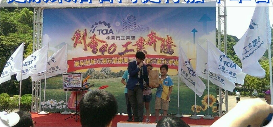 桃園市工業會創會40週年背板前，柯男在戶外舞台與小朋友互動變魔術