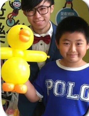 男孩拿著黃色小鴨造型氣球與柯男合照