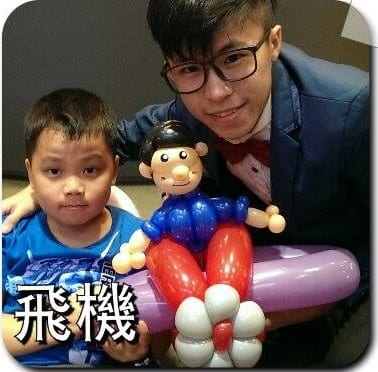 小男孩和柯男拿著人物坐在飛機上的造型氣球