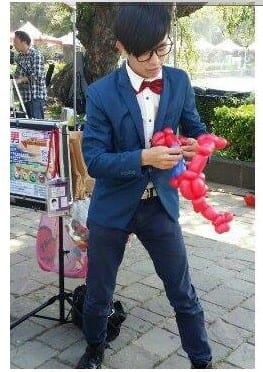 穿藍西裝紅領結的柯男在甄選現場折紅色氣球