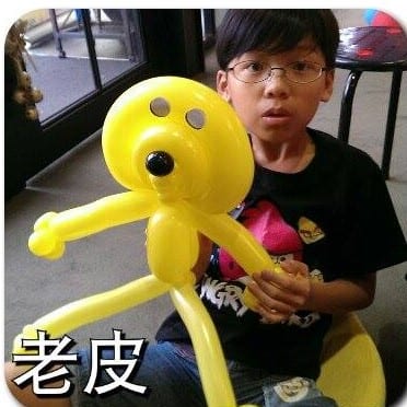 戴眼鏡的男孩拿著黃色老皮造型氣球