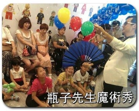 魔術師拿著藍色扇子在診所內表演，小朋友坐地上看