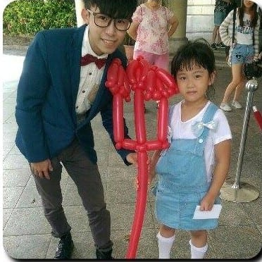 小女孩和柯男拿著紅色惡魔叉子造型氣球合照