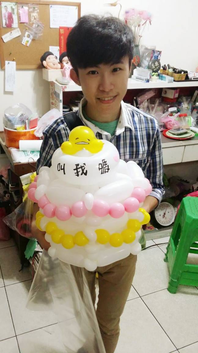 柯男抱著頂端趴著蛋黃哥的三層白色氣球蛋糕帽