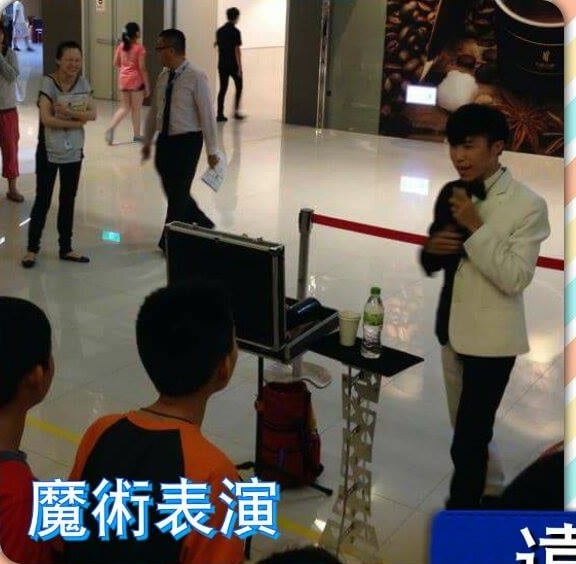 穿白外套黑褲的魔術師在商場中庭表演魔術