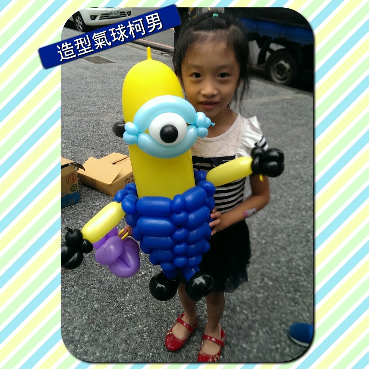 小妹妹抱著大型小小兵造型氣球站在路邊