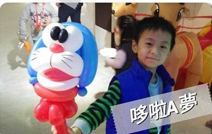 穿藍色背心的男孩拿著哆啦A夢造型氣球
