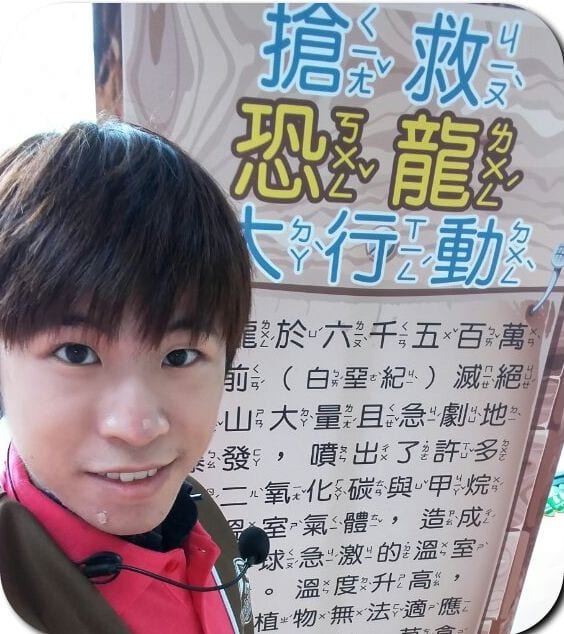 我戴著耳麥在搶救恐龍大行動的關卡海報前自拍
