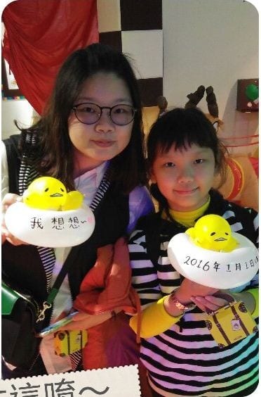 兩個女孩拿著寫字的蛋黃哥造型氣球,蛋白上寫著 2016 年 1 月 1 日