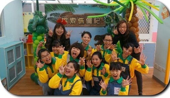 穿黃綠色制服的工作人員在恐龍背板前合照