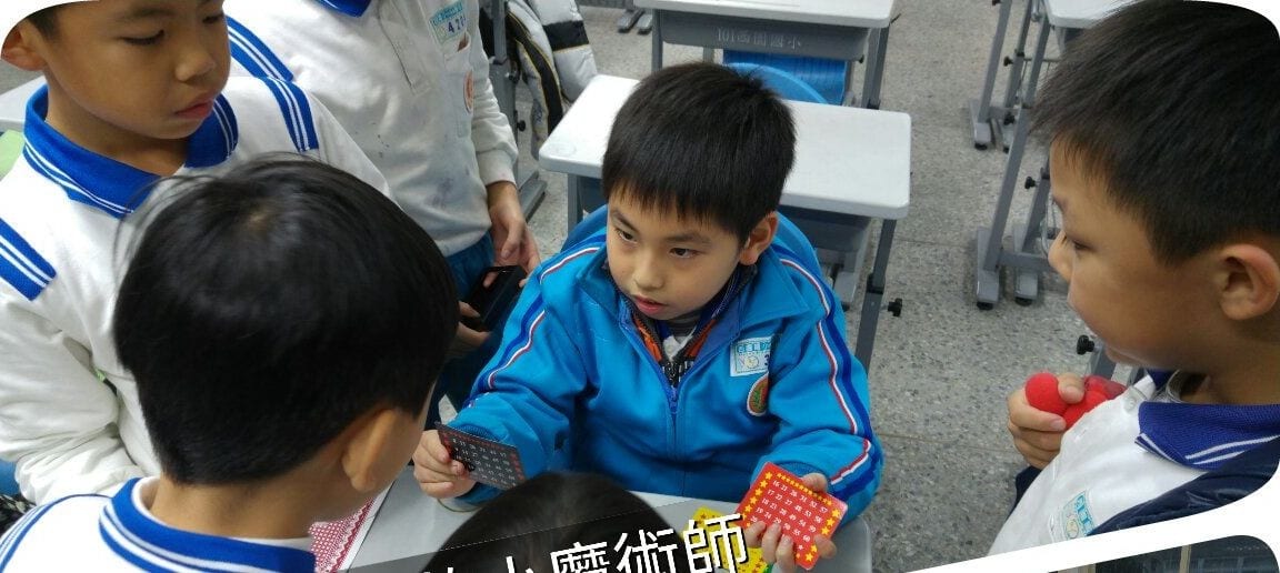 穿運動服的國小學生拿著撲克牌練習魔術