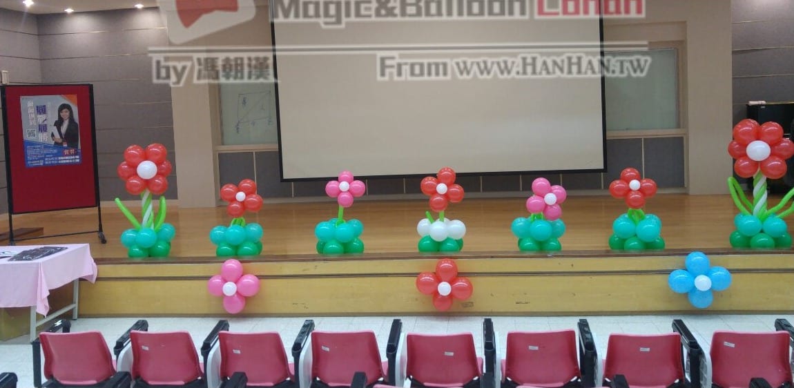 禮堂舞台前一整排紅、粉紅花朵配綠色底座的氣球花柱