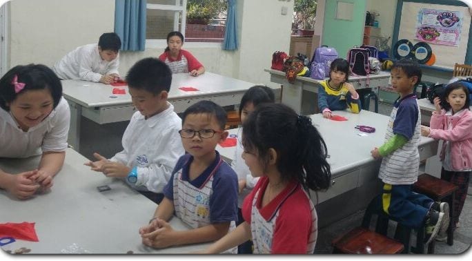 台北中山中正國小魔術課，學生圍著課桌練習紅色小道具