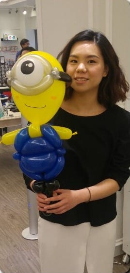 女士拿著小小兵造型氣球站在店裡