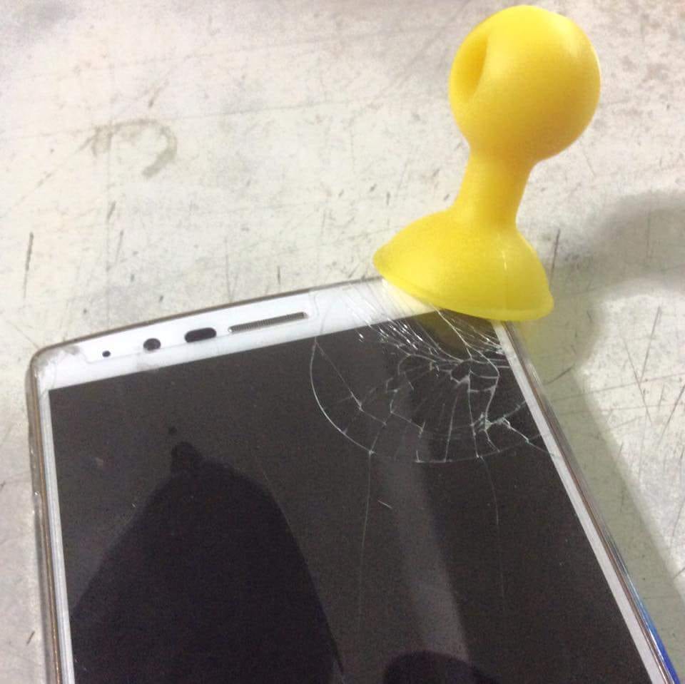黃色吸盤吸在手機鋼化玻璃保護貼上，角落裂成蜘蛛網