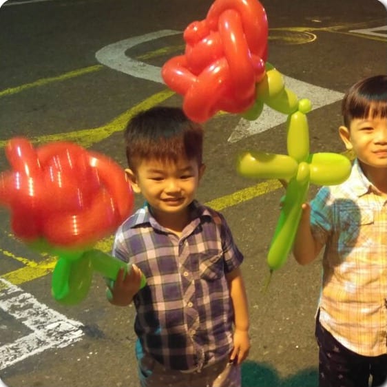 兩個男孩拿著紅色氣球玫瑰花