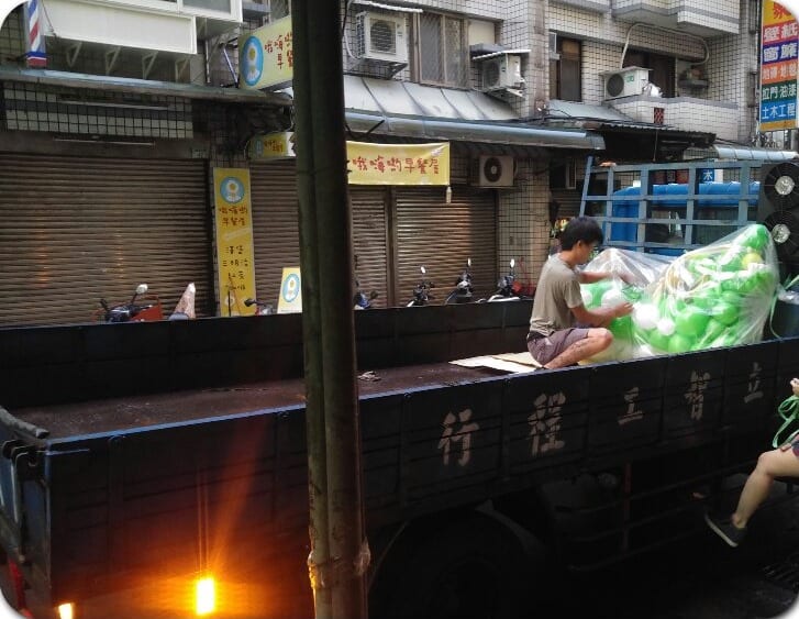 把用透明袋包好的氣球龍舟放上貨車車斗
