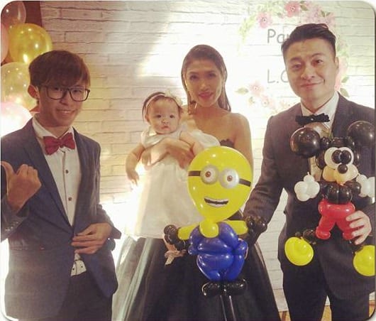 婚禮喜宴上，新娘抱著寶寶和新郎拿著小小兵、米奇造型氣球合照