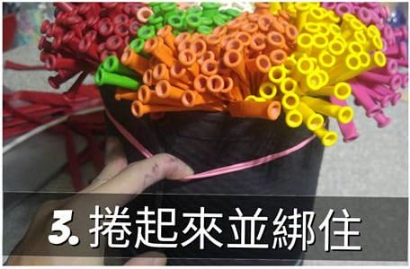 把成束的長條氣球捲起來，用粉紅色繩子綁住