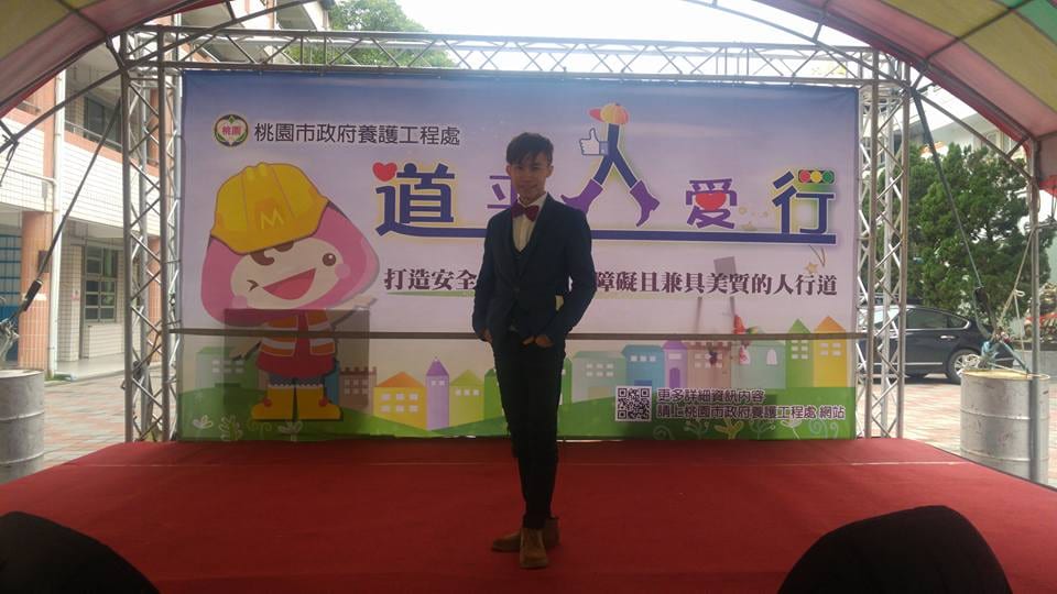 桃園大成國中「道平人愛行」活動舞台，柯男站在養護工程處背板前