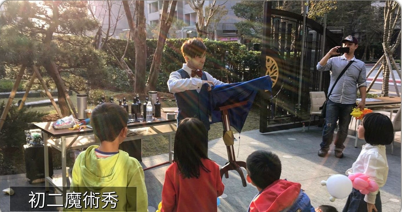 遠雄晴空樹大年初二戶外魔術秀，小朋友圍在藍色桌巾魔術桌前觀看