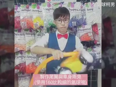 F1 賽車造型氣球教學影片，柯男拿著完成的黃色賽車氣球
