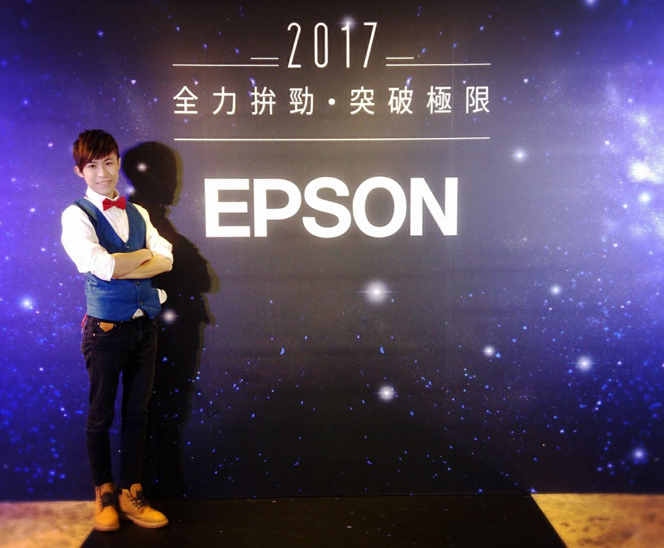 EPSON 尾牙會場星空背板前，柯男穿藍背心紅領結雙手抱胸，背板寫 2017 全力拚勁突破極限